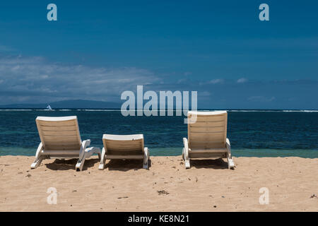 Orario estivo sulla spiaggia e lettini solari. lettini su una spiaggia deserta di bali. Foto Stock