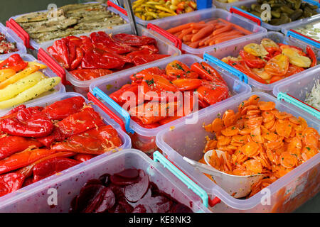 Verdure sottaceto in contenitori di plastica venduti sul mercato verde in stallo Foto Stock