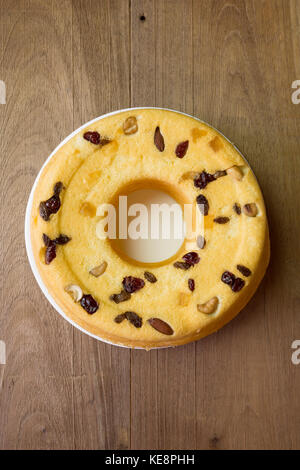 Torta di cotone fatta in casa, miscela di frutti di mandorla, noci di anacardi, mirtilli rossi, mango secchi, uvetta verde, su piatto bianco, su rustico tavolo di legno, piatto Foto Stock