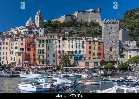 Il porto di Portovenere, sulla costa della Liguria, a nord-ovest dell'Italia. Il Castello dei Doria è sullo sfondo, dietro le righe di colorate case a schiera Foto Stock