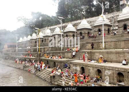 Noemie repetto / le pictorium - nepal - Kathmandu. tempio di Pashupatinath. Patrimonio mondiale dal 1979. - 20/09/2017 - Nepal / kathmandu / Kathmandu - Nepal - Kathmandu. il tempio di Pashupatinath. Patrimonio mondiale dell'umanità dal 1979. la sponda opposta a quella in cui le cremazioni sono effettuate. famiglie stabilirsi lì a preparare il cibo e le offerte prima che galleggiano nel fiume. i turisti si mescolano con le famiglie che priva la cerimonia della sua intimità. Questo lato ha anche 11 templi bianco. Foto Stock