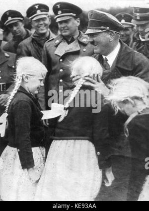 Cancelliere imperiale e socialista nazionale leader Adolf Hitler abbraccia una ragazza bionda con spiralina. non datato. | Utilizzo di tutto il mondo Foto Stock