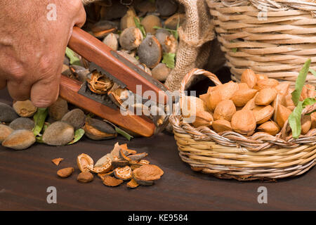 Mandorle su un rustico di legno. Rustica sacco e cestello. schiaccianoci e olio di mandorla. di farina di mandorle. Foto Stock