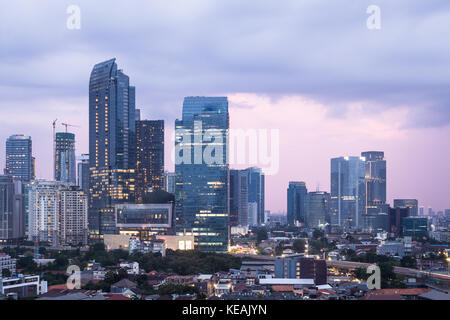 Jakarta, Indonesia - 15 ottobre 2017: il sole tramonta su Giacarta quartiere degli affari con alti edifici adibiti ad uffici e lussuoso condominio le torri in indones Foto Stock