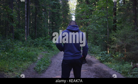 Giovane uomo che indossa un cappello nel bosco. L'atleta è venuto nella foresta per fare sport Foto Stock