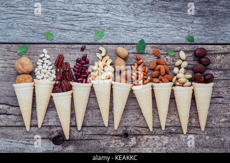Concetto per fatti in casa i dadi vari gelati. dadi misti in cialda coni squallido sfondo in legno.Vista superiore Foto Stock