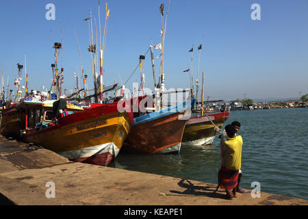 Sud della provincia dello Sri Lanka Mirissa porto di pesca pescatori tirando la corda per legare in barca al porto Foto Stock