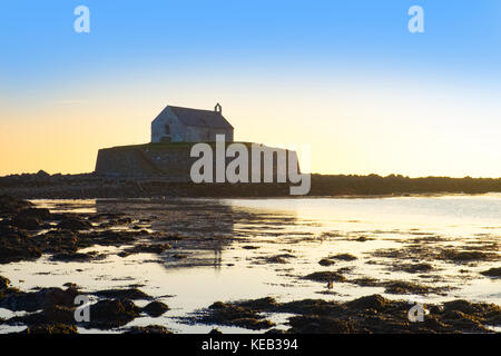 Cwyfan tramonto. La cappella nel mare, al largo di Anglesey, Galles. Foto Stock