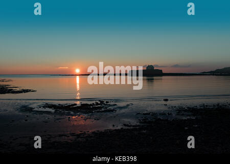 Cwyfan tramonto. La cappella nel mare, al largo di Anglesey, Galles. Foto Stock