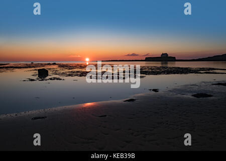 Cwyfan tramonto. La cappella nel mare, al largo di Anglesey, Galles. Foto Stock