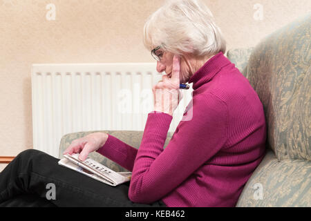 Senior anziani vecchio single una persona donna mantenendo attiva la mente facendo un cruciverba invecchiamento invecchiamento della popolazione Foto Stock