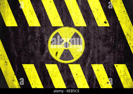 Radioattivo (radiazioni ionizzanti) simbolo di pericolo con il giallo e il nero a strisce dipinte su un massiccio muro di cemento con texture rustico sfondo. Foto Stock
