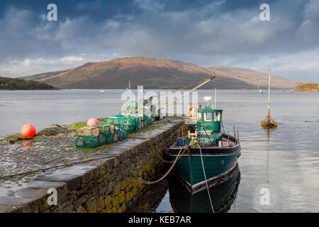 Una barca da pesca e pentole di aragosta al piccolo molo di pietra a Isleornsay, Sleat Peninsula, Isola di Skye, Highland, Scotland, Regno Unito Foto Stock