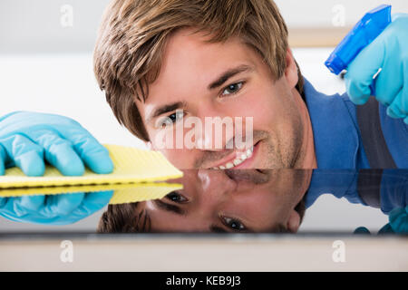 Close-up del lavoratore la mano indossando guanti di gomma e la pulizia del piano del banco Foto Stock