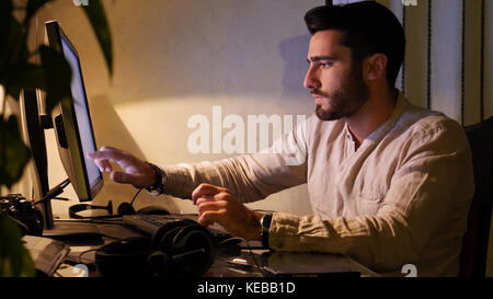 Home lavoratore seduto alla scrivania con computer touchscreen Foto Stock