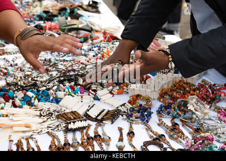 Una donna la contrattazione di un prezzo a un braccialetto store Foto Stock