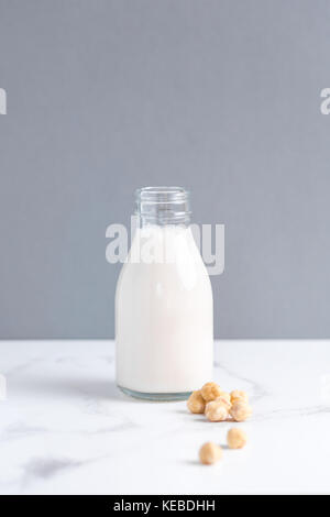 In stile minimalista di stock foto di nocciola in casa senza latte e derivati del latte in un bottiglia di latte contro uno sfondo grigio sul marmo. Foto Stock