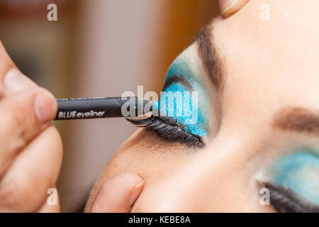 Trucco artisti applicando un ombretto blu su bianco occhi di donna Foto Stock
