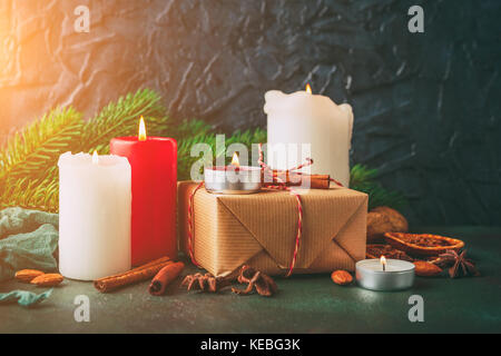 Natale e Anno Nuovo candele accese con un regalo in carta kraft, Abete rami, arance e spezie Foto Stock