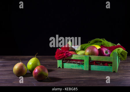 Scatola di frutta con pere selvatiche isolato sul tavolo di legno e uno sfondo scuro. Foto Stock