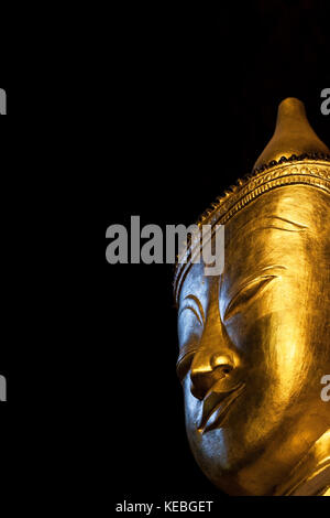 Big Buddha testa con gli occhi chiusi nella contemplazione. Un golden statua del Buddha isolato su sfondo nero in un tempio nella grotta in Thailandia. sacro luogo santo Foto Stock