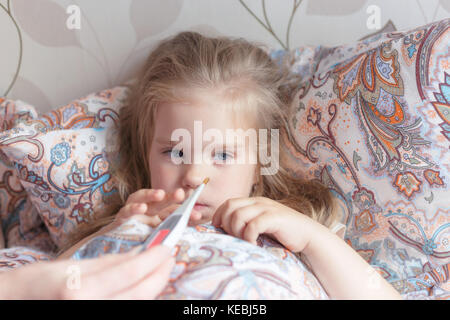 Un freddo bambina giace in una triste letto con la febbre Foto Stock