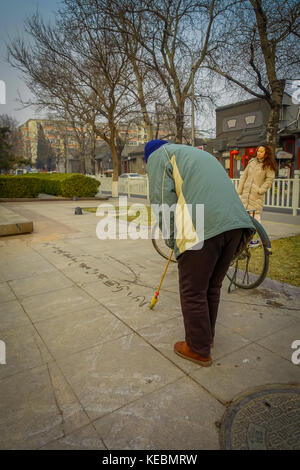 Pechino, Cina - 29 January, 2017: il vecchio uomo cinese pittura con acqua su piastrelle in pietra tradizionale new anni auguri rituale Foto Stock