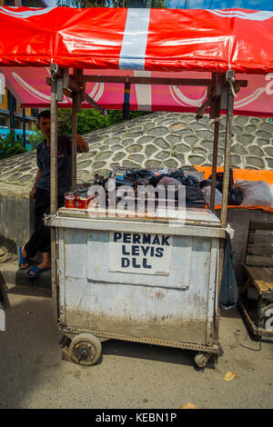 Jakarta, Indonesia - 3 marzo, 2017: locale uomo in piedi accanto alla sua piccola impresa carrello, offrendo le piccole riparazioni Foto Stock