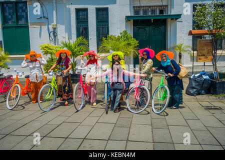 Jakarta, Indonesia - 3 marzo, 2017: gruppo di molto colorate le donne indossando il tradizionale abito indonesiano, alcuni con le biciclette, posa per fotocamera su city plaza Foto Stock