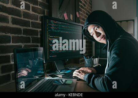 Il male giovane programmatore di computer come hacker e la progettazione dei dati errati hacking del sistema global business informazioni sulla società al fine di scamming riscatto. Foto Stock