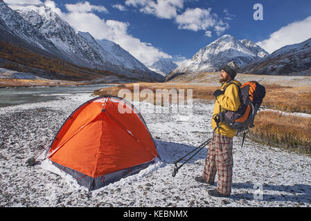 Escursionista con zaino in campeggio in montagna durante la primavera. backpacker con bierd guardando in alto. Foto Stock