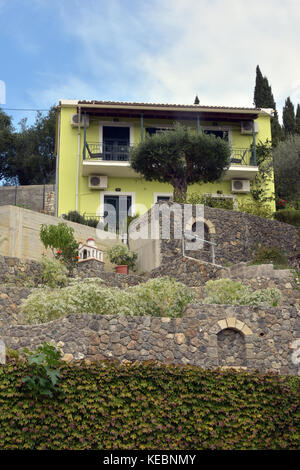 Un dipinto di giallo villa costruita nella roccia e utilizzato come casa vacanze sull'isola greca di Corfu in Grecia vicino al mare. secomd case. Foto Stock