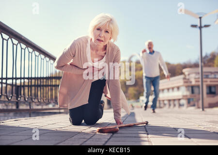 Donna cadere sulle ginocchia mentre soffre di un attacco di cuore Foto Stock