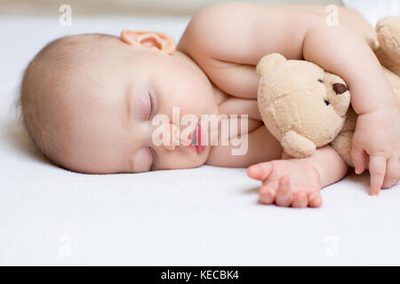 Bambino neonato nel letto, tenendo un orsacchiotto di peluche. Foto Stock