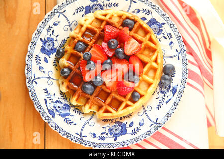 Waffle fatti in casa con mirtilli freschi, fragole e sciroppo d'acero Foto Stock