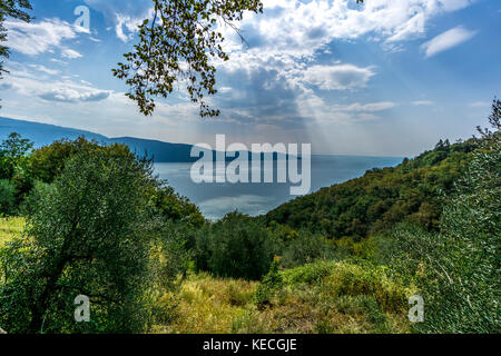 Raggi di sole attraverso le nuvole sopra il lago di garda Foto Stock