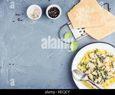 Tagliatelle al salmone, spinaci e salsa cremosa, parmigiano su calcestruzzo sfondo testurizzata Foto Stock