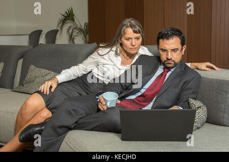 Giovane a casa in formalware con l uomo e la donna guardando sopra la sua spalla nel loro appartamento di città Foto Stock