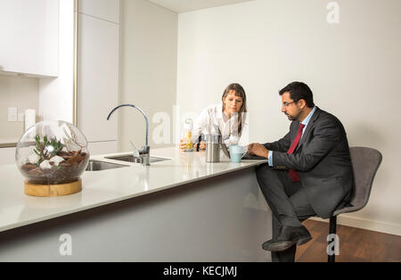 Uomo arabo in formalware lavorando nel suo computer in una cucina del suo appartamento urbano Foto Stock