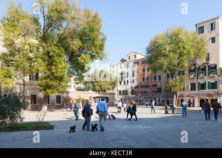 La gente del posto andando sulla loro vita quotidiana e a pochi turisti nel ghetto ebraico nel Campo De Ghetto Novo, Cannaregio, Venezia, Italia Foto Stock