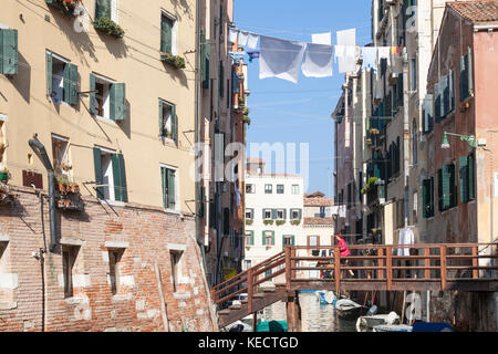 Donna con il suo cane attraversando Ponte De Ghetto Novo , Cannaregio, Venezia, Italia il suo cammino nel veneziano ghetto ebraico. Gli alti edifici sono tipici Foto Stock