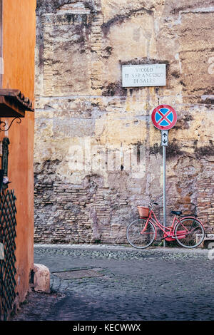 Una rosa moto parcheggiate in uno indossato un muro di mattoni in italia a Roma il quartiere di trastevere Foto Stock