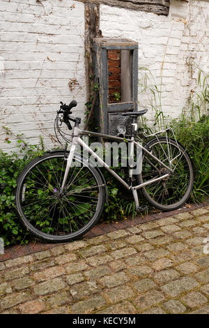 Giugno 2017 - moderna bicicletta bici sinistra appoggiata contro un vecchio muro a Thame, Oxfordshire, Inghilterra. Foto Stock