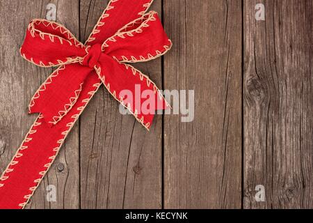 Rustico rosso Natale Arco e nastro bordo diagonale, sopra vista su uno sfondo di legno vecchio Foto Stock