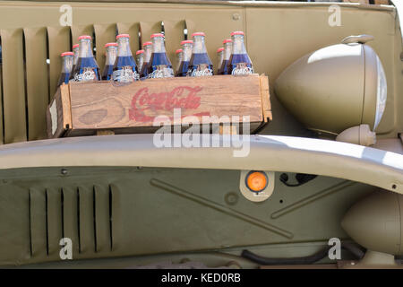 Cassano Magnago, Italia - 8 ottobre 2017: Cassetta di legno con bottiglie di vetro coca cola inserite all'interno poggia su un veicolo militare dell'unione Foto Stock
