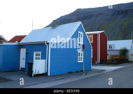 Blu e rosso tradizionali case islandesi in legno sul fronte strada e montagna in background, Isafjordur, Westfjords, Islanda Foto Stock