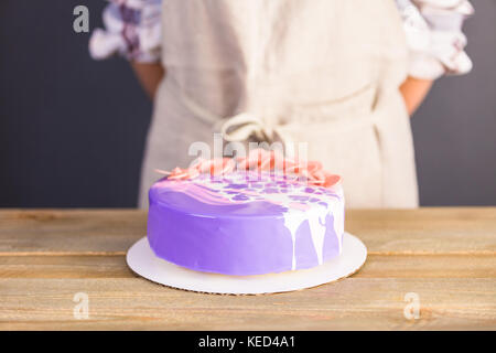 Pastre shef realizzare mousse torta con specchio viola smalto e decorate con cioccolato fiori rosa. Foto Stock