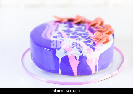 Pastre shef realizzare mousse torta con specchio viola smalto e decorate con cioccolato fiori rosa. Foto Stock