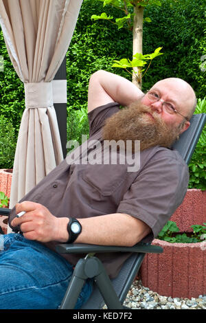 Mann mit langem Bart erholt sich im Liegestuhl Foto Stock