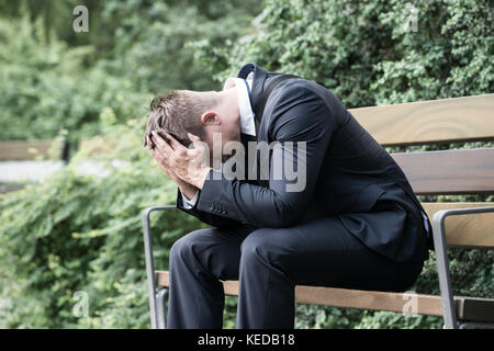 Foto sconvolto giovane impreditore seduta sul banco di lavoro Foto Stock